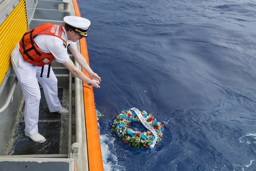 Cmdr. Paul J. Tortora, commanding officer, Military Sealift Command Ship Support Unit Guam lowers a wreath into the ocean off the coast of Naval Base Guam during a National Maritime Day commemoration to honor all fallen civilian mariners, May 22, 2026.