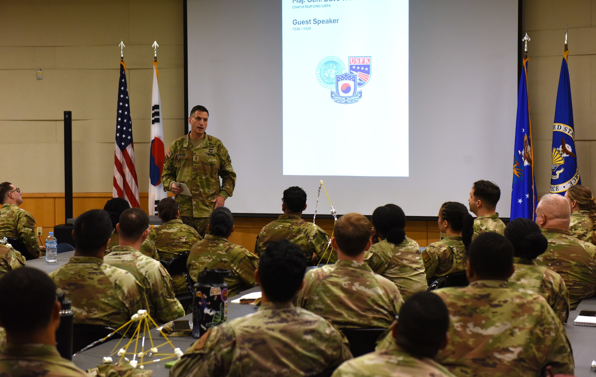 U.S. Army Maj. Gen. Dave Womack, United States Forces Korea chief of staff, speaks to Frontline Leadership Course participants at Osan Air Base, Republic of Korea, July 14, 2026. The 694th Intelligence, Surveillance and Reconnaissance Group and USFK J2 staff hosted the three-day course for 52 Airmen from Osan Air Base and Camp Humphreys. Spaghetti towers displayed on the tables were constructed during a hands-on project management exercise focused on project management, teamwork and adaptability. (U.S. Air Force photo by Master Sgt. John Jenkins)