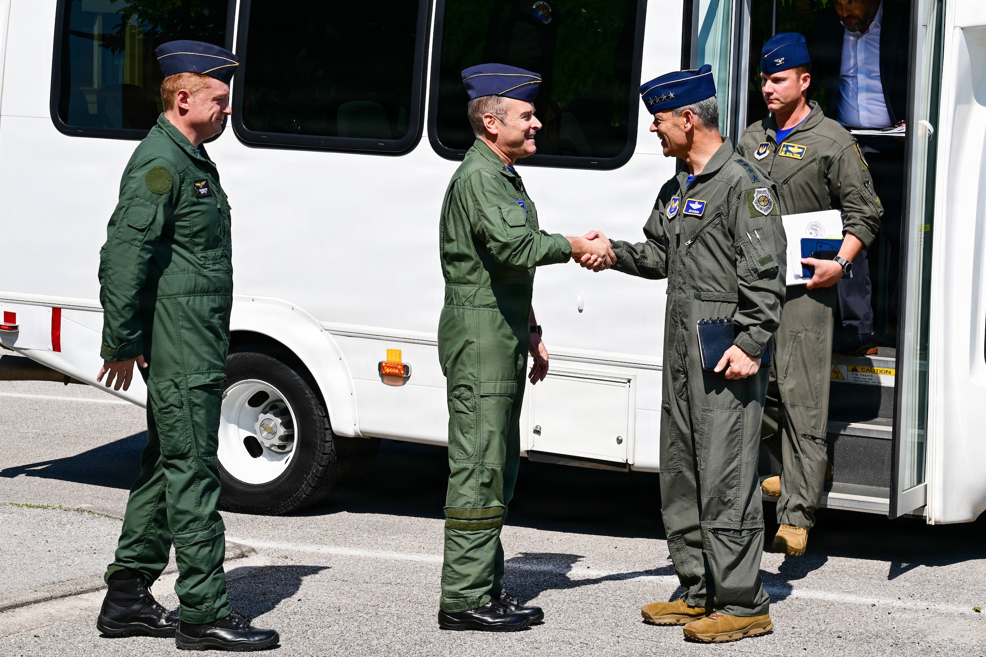 A man shakes another man's hand as he exits a vehicle.