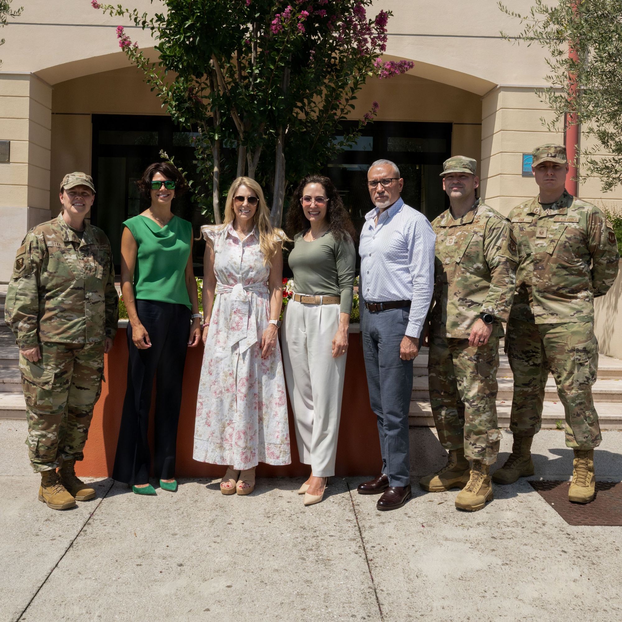 A group of men and women pose for a photo outside.