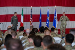 Two men stand on a stage speaking to a large audience.