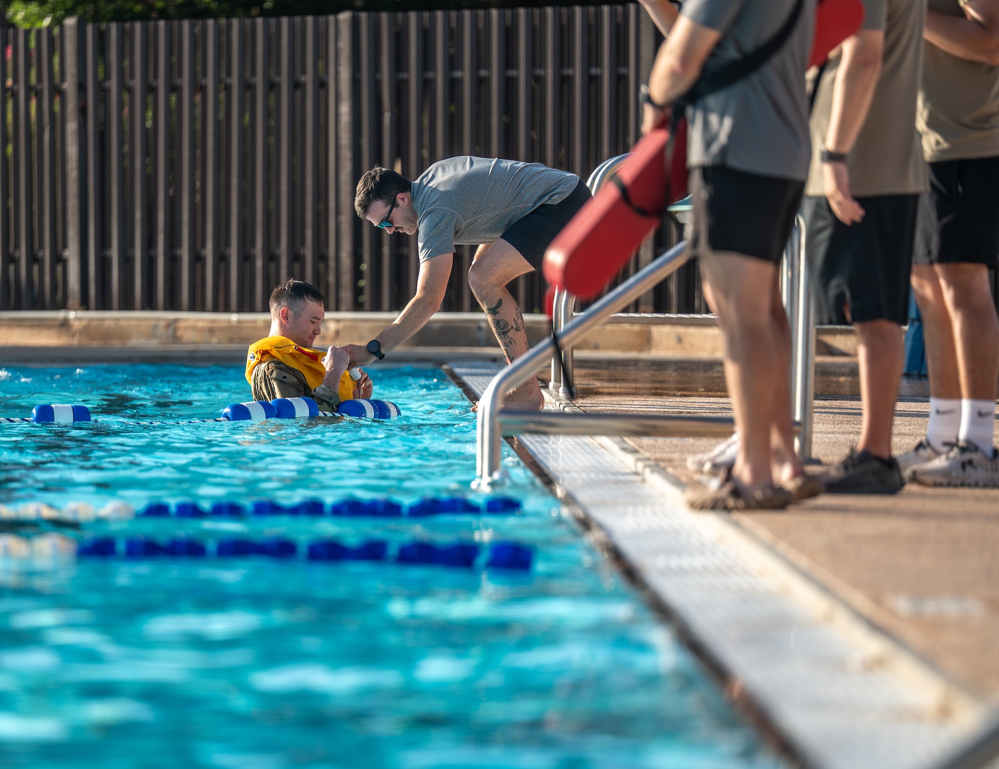 U.S. Air Force Master Sgt. Russel Batson, 137th Special Operations Support Squadron survival, evasion, resistance, and escape (SERE) specialist, assists an Airman assigned to Altus Air Force Base (AFB) with his inflatable life preserver during Water Survival Training at Altus AFB, Oklahoma, July 10, 2026. In the Altus AFB pool, SERE specialists drilled participants on utilizing emergency survival gear. (U.S. Air Force photo by Airman 1st Class Emma Wright)