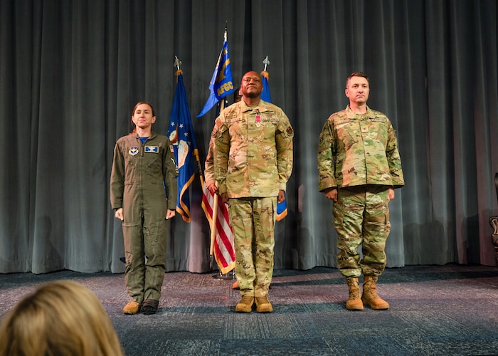 From left, U.S. Air Force Col. Ellen Canup, Curtis E. LeMay Center commander, Col. Damian Holtzclaw, Air Force Global College outgoing commander, and Col. Andrew Looser, Air Force Global College incoming commander, stand at attention during the playing of the national anthem during a change of command ceremony at Maxwell Air Force Base, Ala., July 10, 2026.