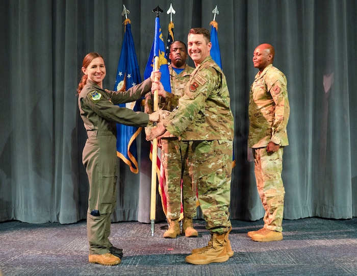 U.S. Air Force Col. Andrew Looser, the incoming commander of Air Force Global College, center, receives the guidon from Col. Ellen Canup, Curtis E. LeMay Center commander, during a change of command ceremony at Maxwell Air Force Base, Alabama July 10, 2026.