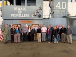 A large group of people stand on a mock-up of a Navy aircraft carrier deck.