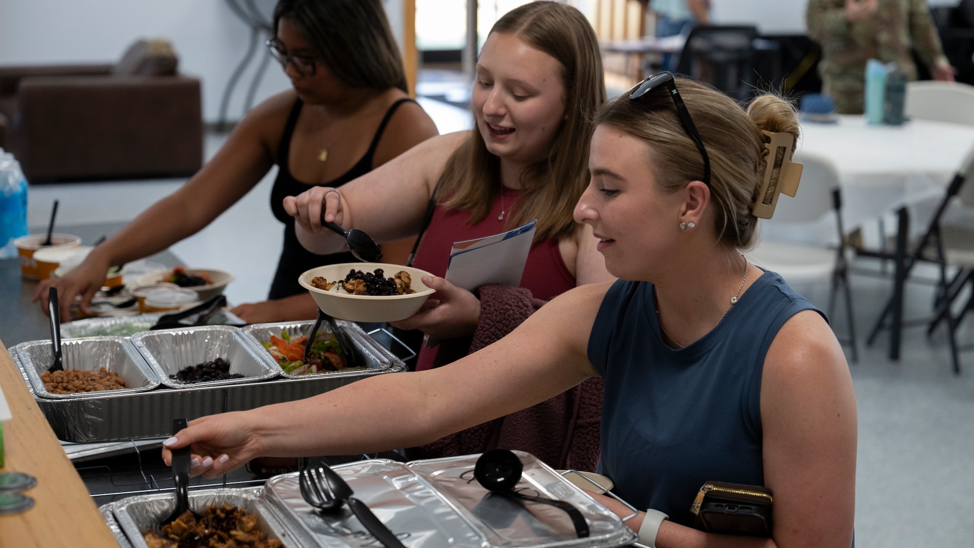 People serve themselves food at deployed family dinner.
