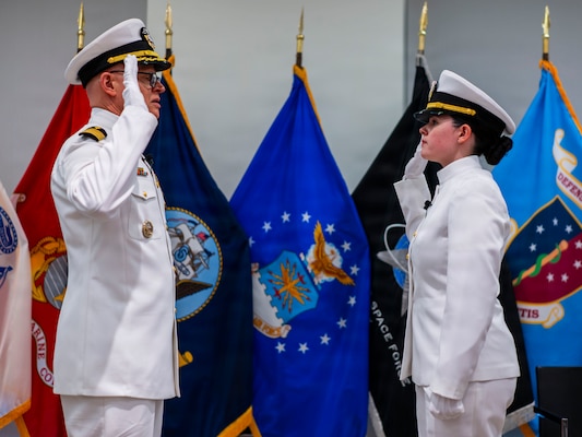 (260710-N-AJ782-1142) FALLS CHURCH, Va. From left to right, U.S. Navy Capt. Lonnie S. Hosea, Bureau of Medicine and Surgery senior health policy advisor, administers the oath of office to his daughter, Ensign Jenna Hosea Baker, a nurse assigned to Walter Reed National Military Medical Center, as part of a joint ceremony featuring the retirement of Hosea and the commissioning of Baker at Defense Health Headquarters in Falls Church, Virginia, July 10, 2026. The ceremony highlighted a continuing legacy of service for Navy Medicine as Hosea closed out a 30-year career and Baker took her first steps into the Nurse Corps. (U.S. Navy photo by Kevin Ray J. Salvador)