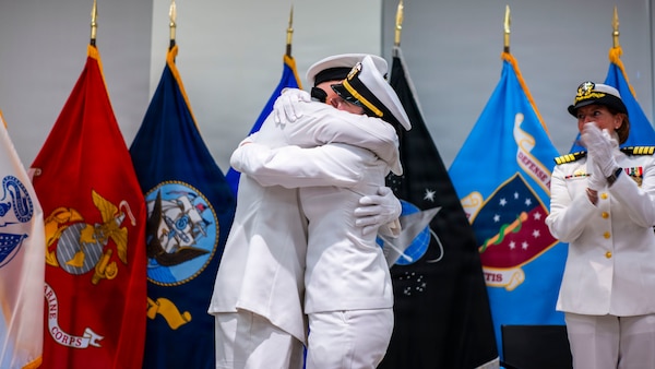 (260710-N-AJ782-1143) FALLS CHURCH, Va. From left to right, U.S. Navy Capt. Lonnie S. Hosea, Bureau of Medicine and Surgery senior health policy advisor, embraces his daughter, Ensign Jenna Hosea Baker, a nurse assigned to Walter Reed National Military Medical Center, after administering the oath of office as part of a joint ceremony featuring the retirement of Hosea and the commissioning of Baker at Defense Health Headquarters in Falls Church, Virginia, July 10, 2026. The ceremony highlighted a continuing legacy of service for Navy Medicine as Hosea closed out a 30-year career and Baker took her first steps into the Nurse Corps. (U.S. Navy photo by Kevin Ray J. Salvador)