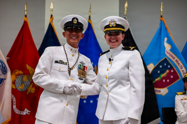 (260710-N-AJ782-1181) FALLS CHURCH, Va. From right to left, U.S. Navy Ensign Jenna Hosea Baker, a nurse assigned to Walter Reed National Military Medical Center, poses for a photo with Senior Chief Petty Officer Roberto C. Songco, Naval Support Activity Bethesda senior enlisted leader, as part of a joint ceremony featuring the retirement of her father at Defense Health Headquarters in Falls Church, Virginia, July 10, 2026. The retirement of Capt. Lonnie S. Hosea, Bureau of Medicine and Surgery senior health policy advisor, and the commissioning of Baker highlighted a continuing legacy of service for Navy Medicine as Hosea closed out a 30-year career and Baker took her first steps into the Nurse Corps. (U.S. Navy photo by Kevin Ray J. Salvador)
