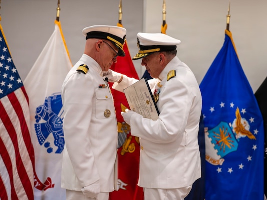 (260710-N-AJ782-1287) FALLS CHURCH, Va. From left to right, U.S. Navy Capt. Lonnie S. Hosea, U.S. Navy Bureau of Medicine and Surgery (BUMED) senior health policy advisor, is awarded with the Defense Meritorious Service Medal by Rear Adm. Matthew Case, acting Surgeon General of the Navy and acting chief, BUMED, as part of a joint retirement and commissioning ceremony at Defense Health Headquarters in Falls Church, Virginia, July 10, 2026. Hosea and his daughter, Ensign Jenna Hosea Baker, who is a nurse assigned to Walter Reed National Military Medical Center, highlighted a continuing legacy of service for Navy Medicine as Hosea closed out a 30-year career and Baker took her first steps into the Nurse Corps. (U.S. Navy photo by Kevin Ray J. Salvador)