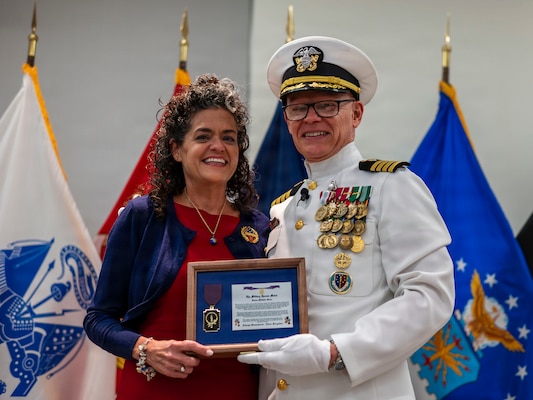 (260710-N-AJ782-1324) FALLS CHURCH, Va. From left to right, Deanna McAlister Hosea receives the Military Spouse Medal from her husband, U.S. Navy Capt. Lonnie S. Hosea, Bureau of Medicine and Surgery senior health policy advisor, as part of a joint retirement and commissioning ceremony at Defense Health Headquarters in Falls Church, Virginia, July 10, 2026. Hosea and his daughter, Ensign Jenna Hosea Baker, who is a nurse assigned to Walter Reed National Military Medical Center, highlighted a continuing legacy of service for Navy Medicine as Hosea closed out a 30-year career and Baker took her first steps into the Nurse Corps. (U.S. Navy photo by Kevin Ray J. Salvador)