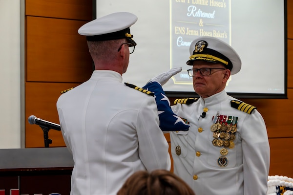 (260710-N-AJ782-1531) FALLS CHURCH, Va. U.S. Navy Capt. Lonnie S. Hosea, Bureau of Medicine and Surgery senior health policy advisor, salutes the flag as part of a joint retirement and commissioning ceremony at Defense Health Headquarters in Falls Church, Virginia, July 10, 2026. Hosea and his daughter, Ensign Jenna Hosea Baker, who is a nurse assigned to Walter Reed National Military Medical Center, highlighted a continuing legacy of service for Navy Medicine as Hosea closed out a 30-year career and Baker took her first steps into the Nurse Corps. (U.S. Navy photo by Kevin Ray J. Salvador)