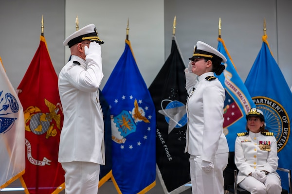 (260710-N-AJ782-1582) FALLS CHURCH, Va. From left to right, U.S. Navy Capt. Lonnie S. Hosea, Bureau of Medicine and Surgery senior health policy advisor, salutes his daughter, Ensign Jenna Hosea Baker, a nurse assigned to Walter Reed National Military Medical Center, as part of a joint ceremony featuring the retirement of Hosea and the commissioning of Baker at Defense Health Headquarters in Falls Church, Virginia, July 10, 2026. The ceremony highlighted a continuing legacy of service for Navy Medicine as Hosea closed out a 30-year career and Baker took her first steps into the Nurse Corps. (U.S. Navy photo by Kevin Ray J. Salvador)
