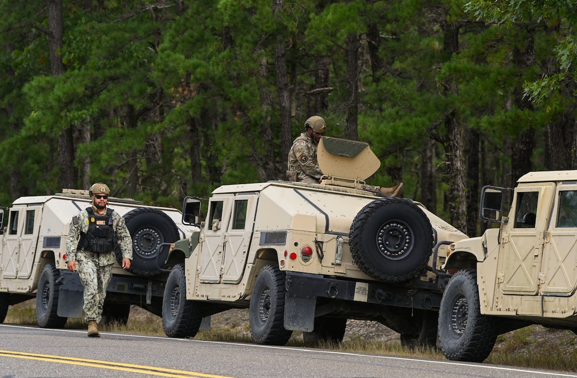 Sailors and Airmen with a security forces squadron deploy in a Humvee convoy during a joint base exercise.