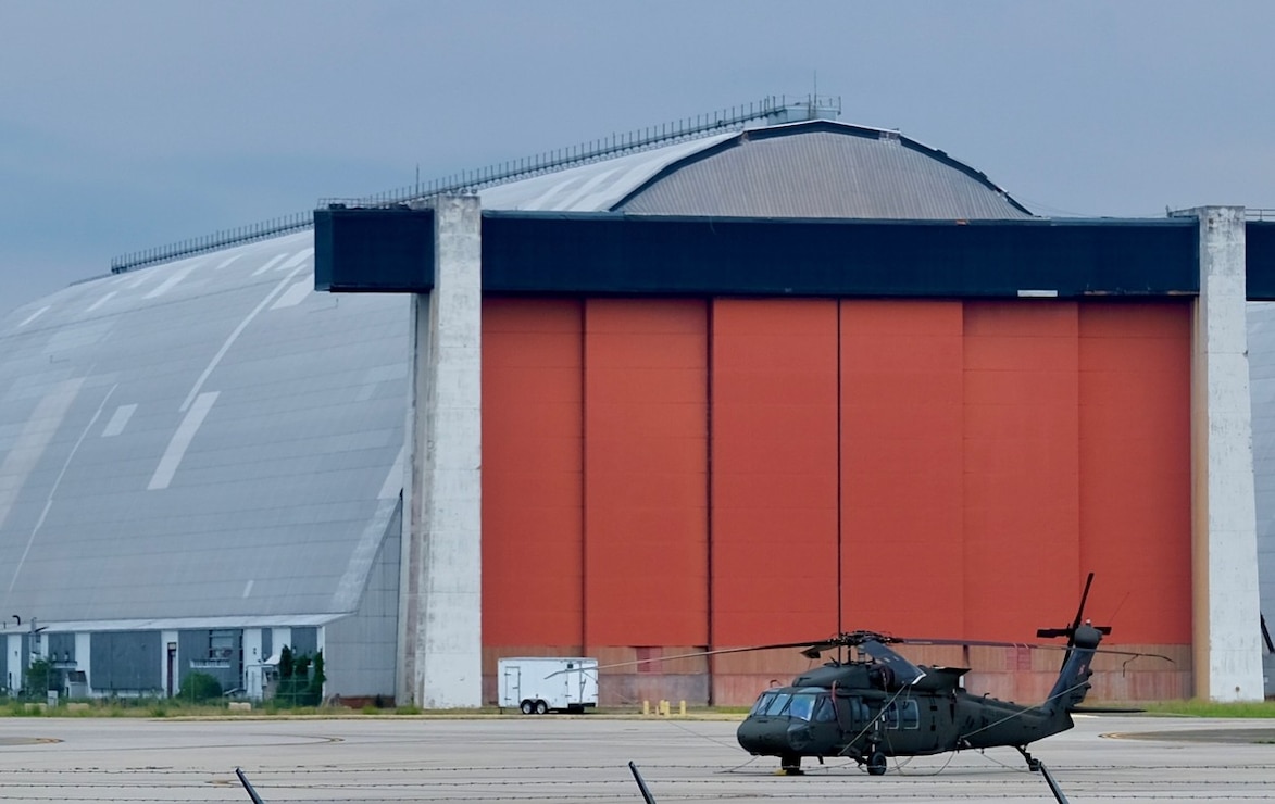 An H-60 assigned to the Army National Guard sits ready at the ramp with Hangar Five in the background.