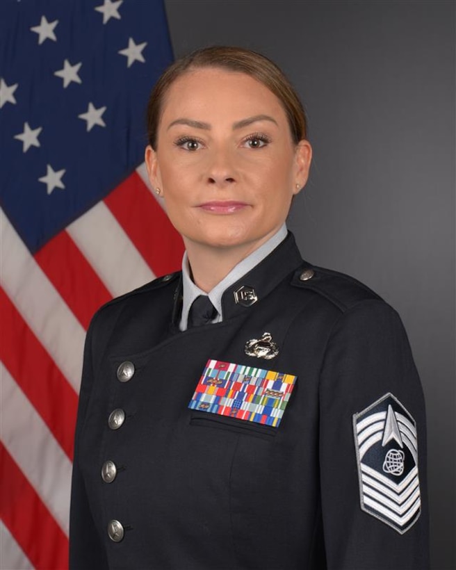 CMSgt Rodriguez in uniform for portrait photo with flag in back