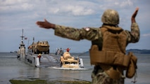 A U.S. Navy seaman uses hand signals to guide a Humvee offloading from a transport vessel at Pohang Port, South Korea, during CJLOTS 2026.