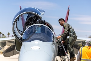 Maj. Kevin Ueunten, T-7A test director, AFOTEC Det 5, climbs into the cockpit of a T-7A Red Hawk at Edwards Air Force Base, CA on June 25, 2026. This marked the first joint test sortie with both developmental and operational test aircrew. The milestone positions the Airpower Foundations Combined Test Force at Edwards to begin combined developmental and operational test flights, ultimately accelerating capability for the warfighter. (Air Force photo by Christian Raterman)