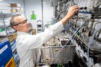 Matthew Yates, Ph.D., U.S. Naval Research Laboratory research scientist, adjusts the flow rate of gas for material generation in the mobile biomanufacturing system in Washington, D.C., June 23, 2026. Scientists at NRL are developing continuous biomanufacturing technologies designed to produce critical materials more efficiently, sustainably, and closer to where they are needed. (U.S. Navy photo by Sarah Peterson)