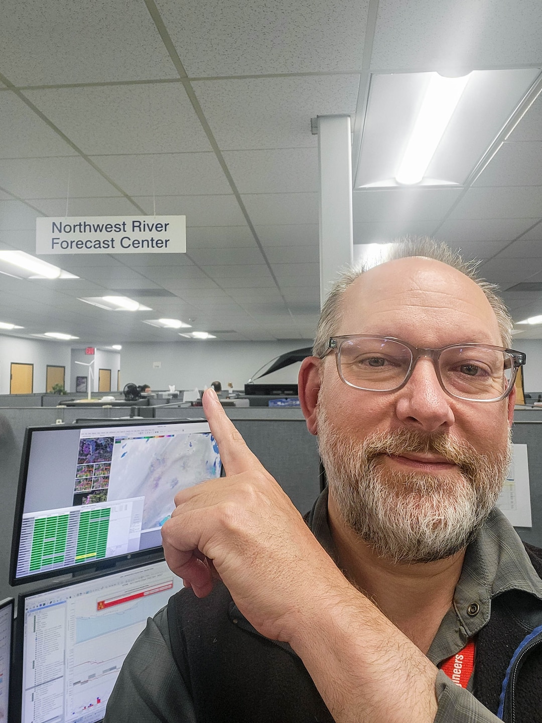 A selfie photo of a person pointing at a sign that reads "Northwest River Forecast Center"