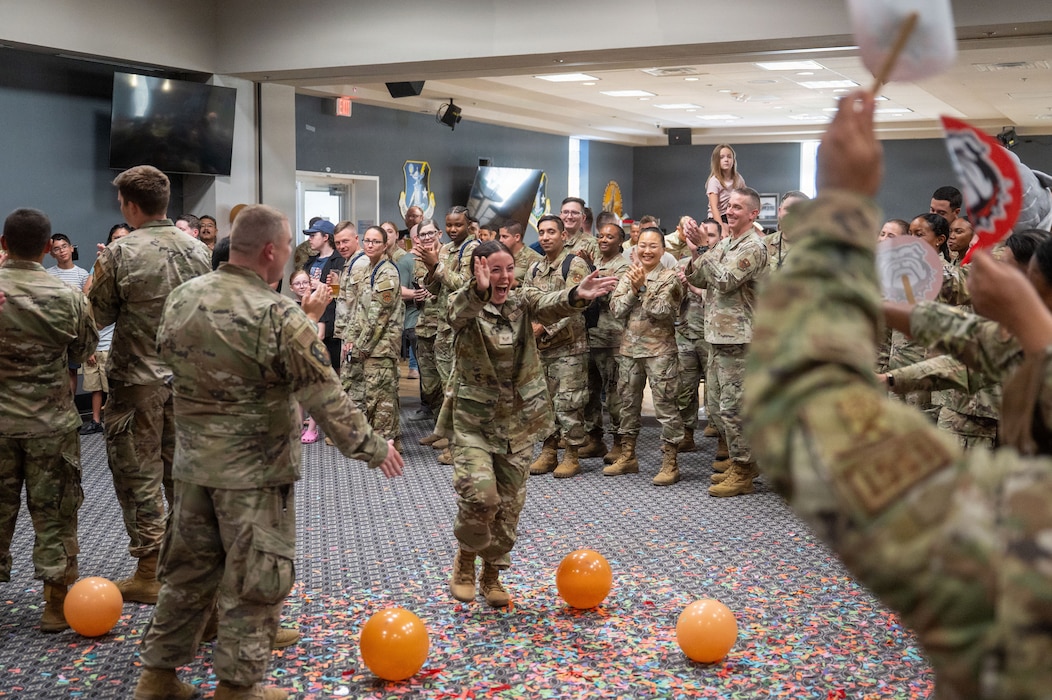 A service member is gives high fives to service members in a line. Confetti is in the air.