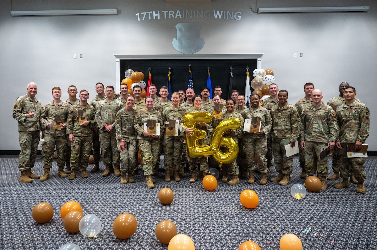 A group of service members pose for a group photo with a 26 balloon in the front