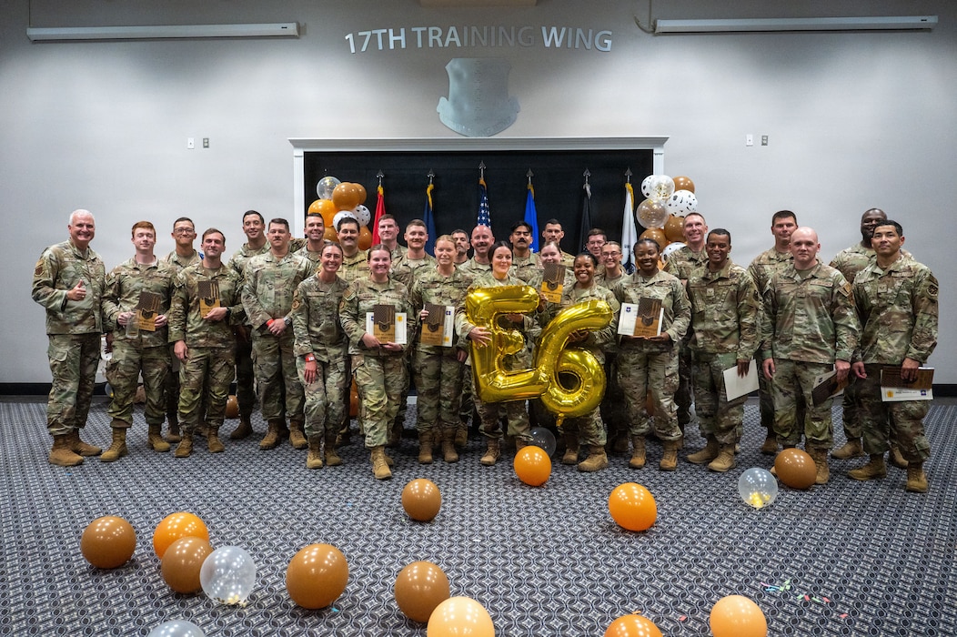 A group of service members pose for a group photo with a 26 balloon in the front