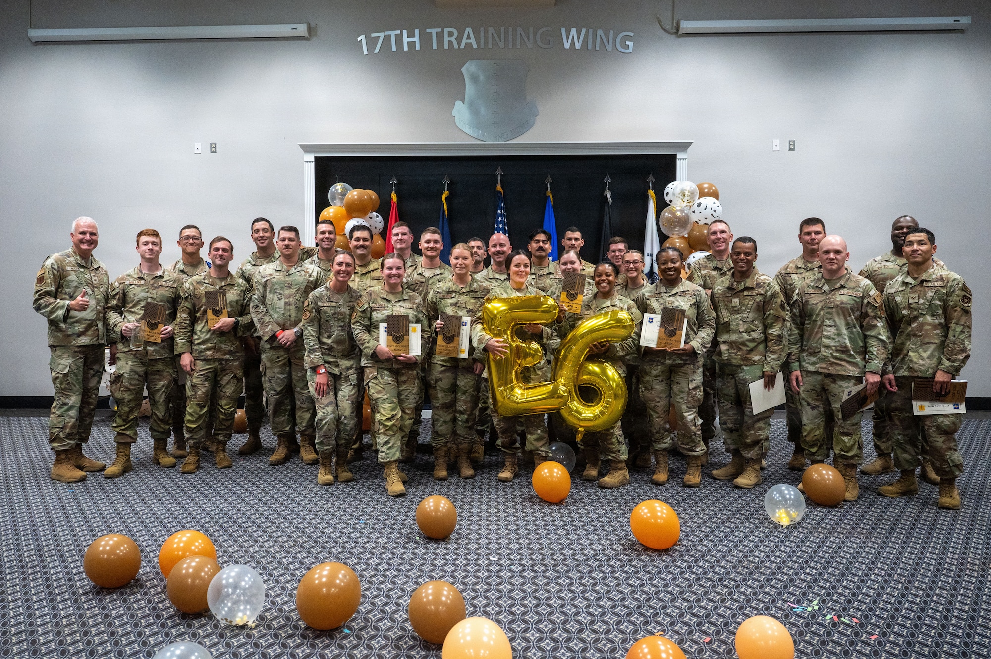 A group of service members pose for a group photo with a 26 balloon in the front