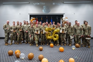 A group of service members pose for a group photo with a 26 balloon in the front