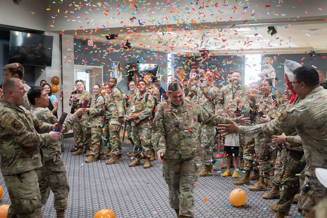 A service member is gives high fives to service members in a line. Confetti is in the air.