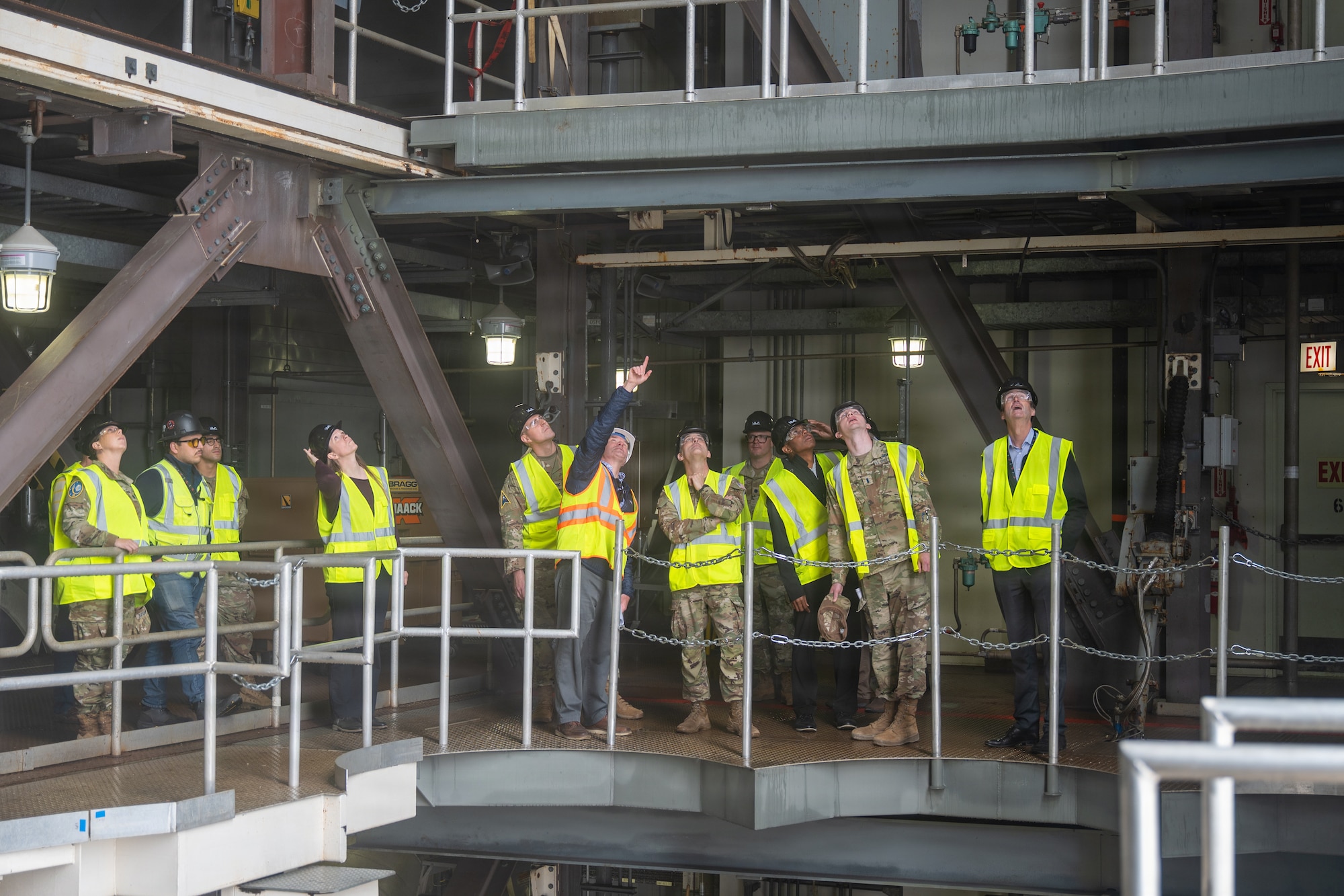 People in safety gear look up in a launch facility.