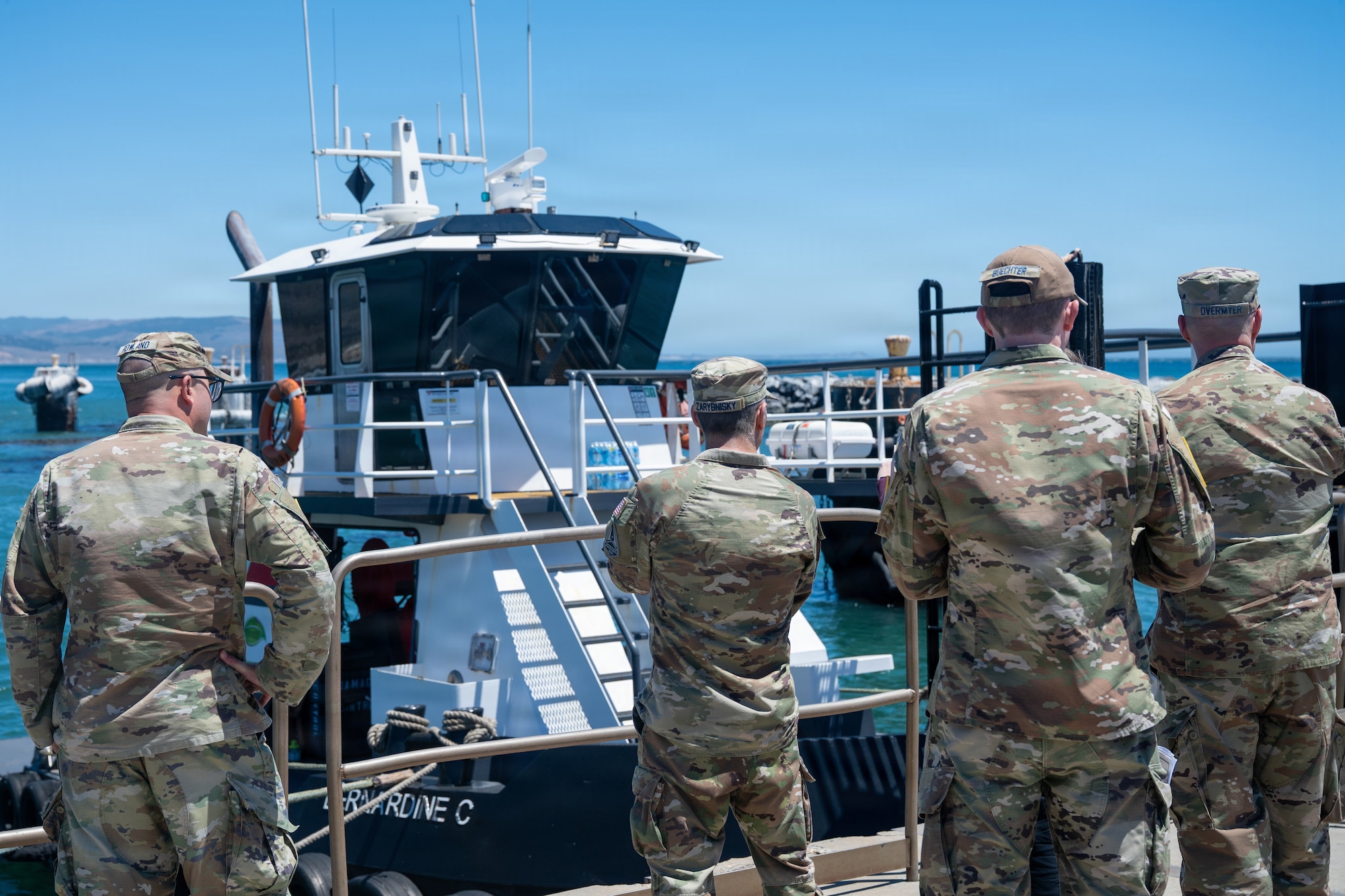 Government workers look at a boat in the water.