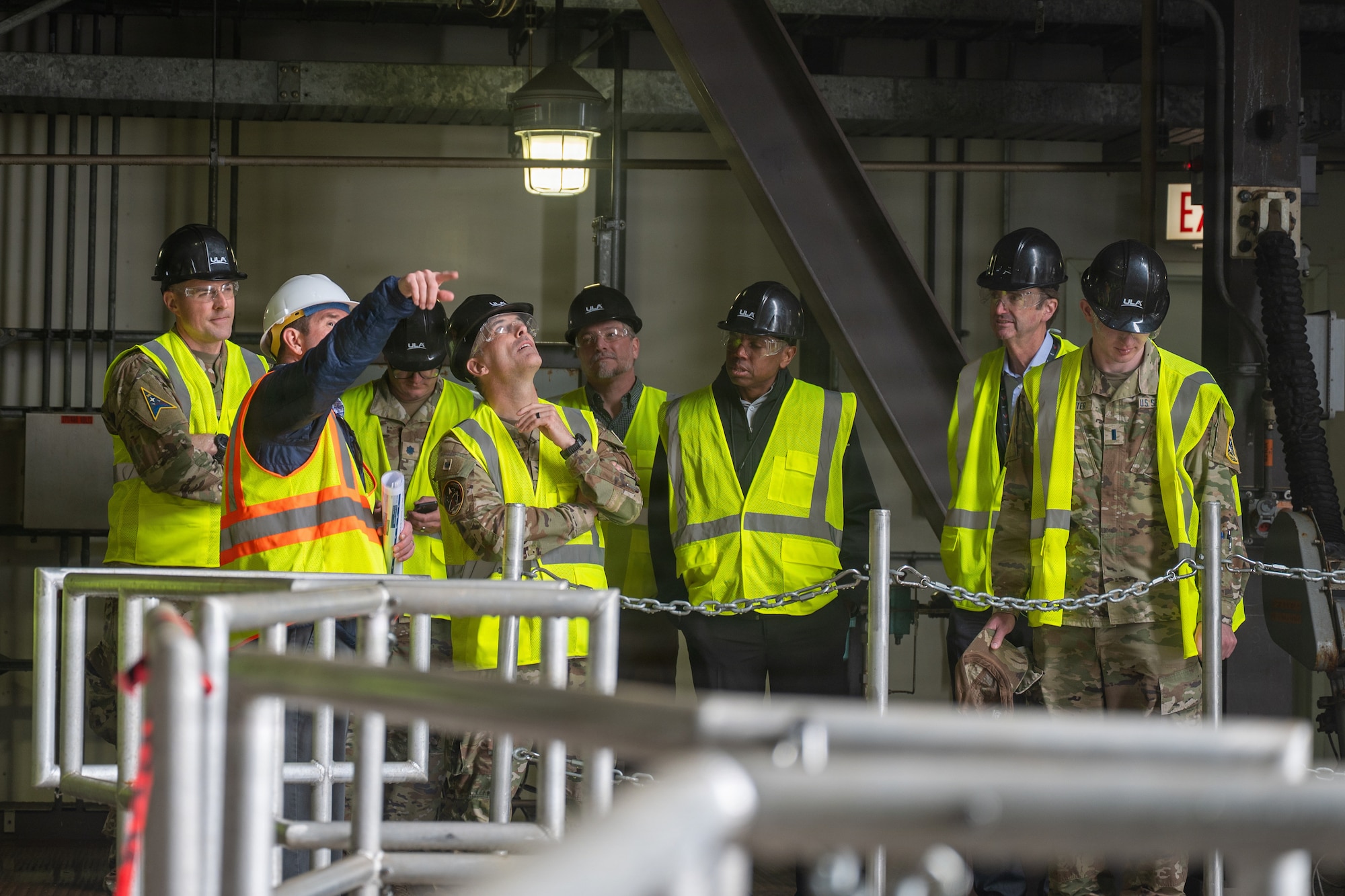 A man points ups surrounded by people in safety gear.