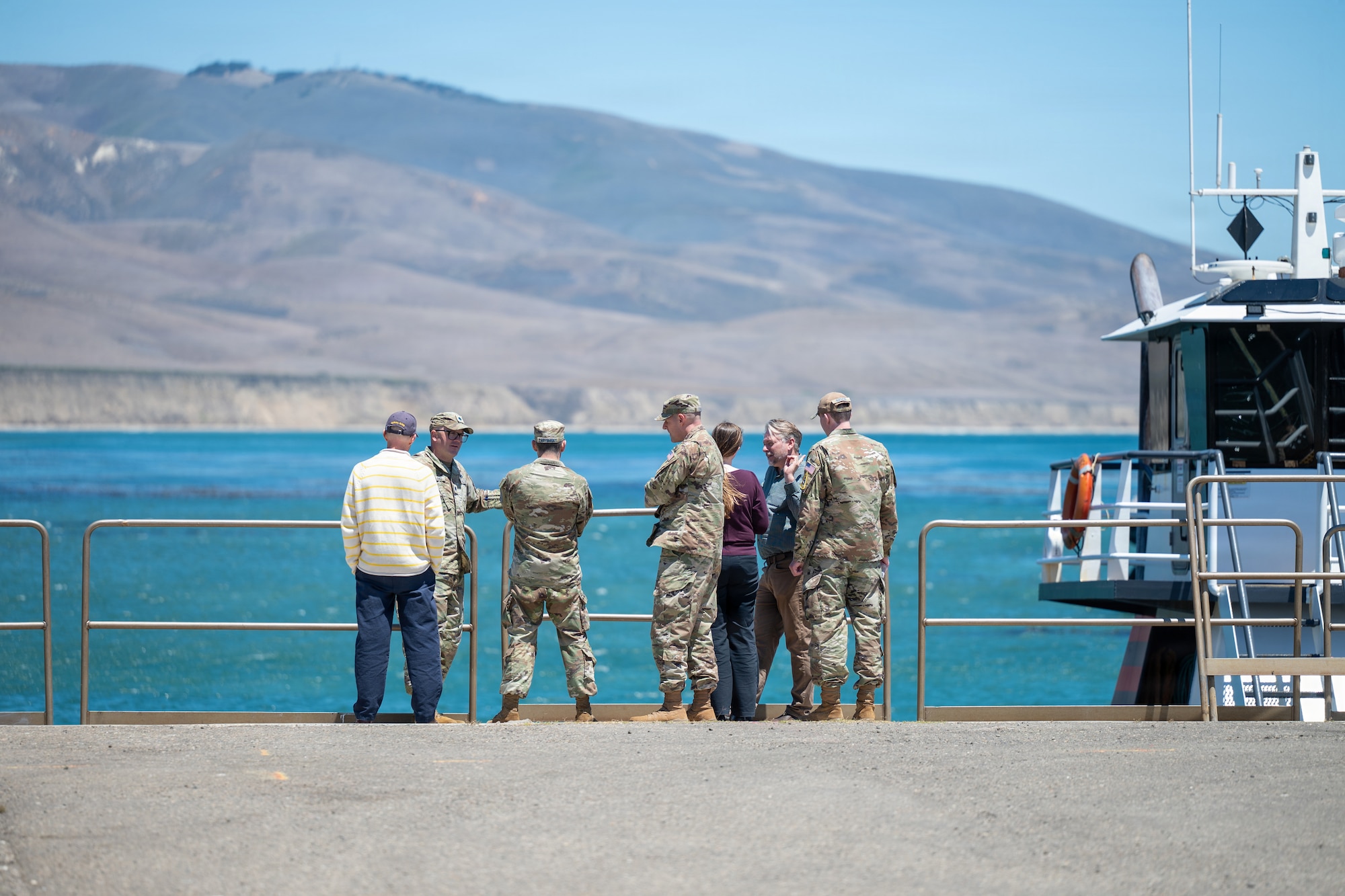 Government workers look out into the ocean near the beach.