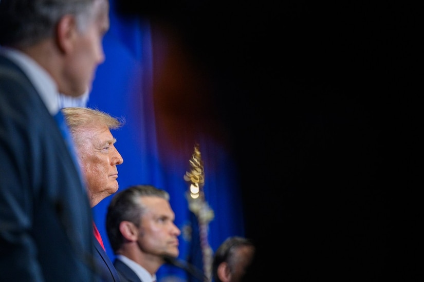 A side view of President Donald J. Trump and Secretary of War Pete Hegseth against a blue background.