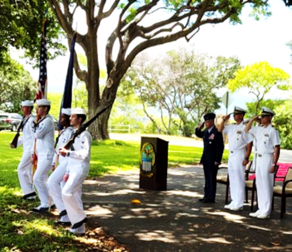 US military service men salute as a color guard marches by.