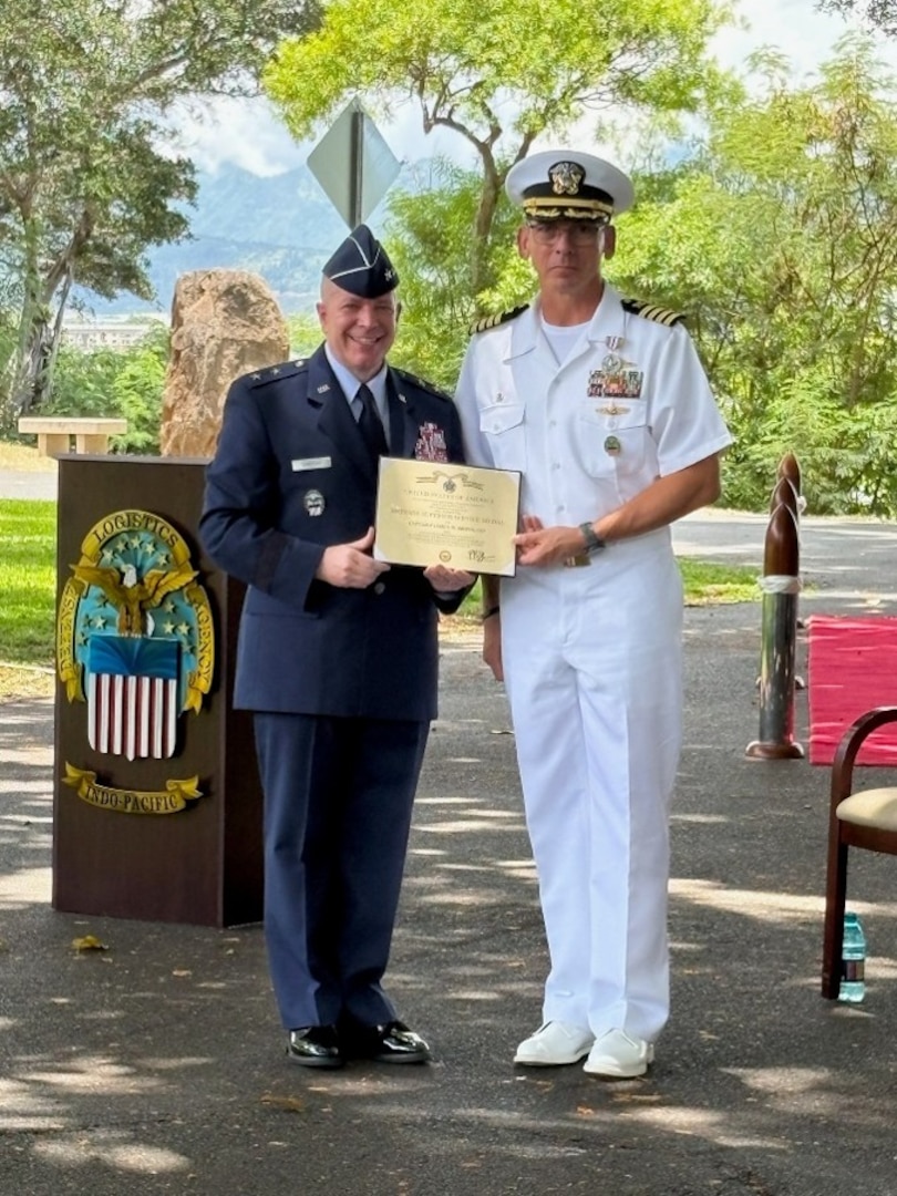 Two U.S. military service men pose with a plaque.