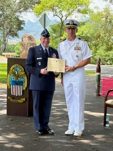 Two U.S. military service men pose with a plaque.
