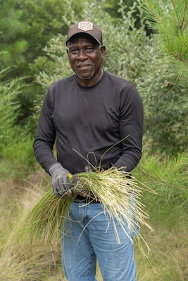 An individual holds sweetgrass, a native coastal perennial grass prized for its strength and flexibility, in his hands for the camera.