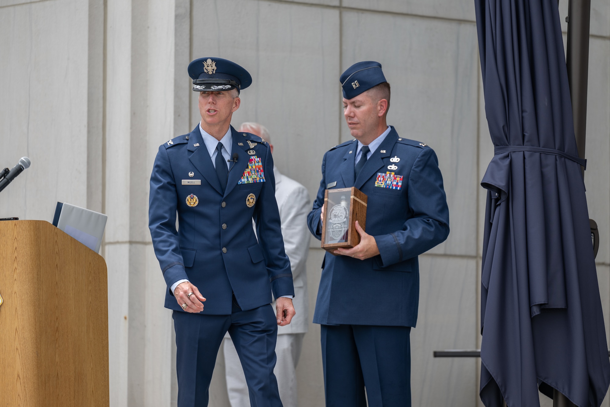 Outgoing Arnold Engineering Development Complex Commander Col. Grant Mizell, left, shares one of his contributions to the AEDC time capsule unveiled June 27, 2026, during the AEDC 75th anniversary open house celebration at Arnold Air Force Base, Tenn., headquarters of AEDC. Mizell included in the capsule a bottle of Jack Daniel’s whiskey specially distilled for the 75th anniversary of AEDC. Pictured holding the bottle is AEDC Executive Officer Capt. Nathan Tedder. (U.S. Air Force photo by Keith Thornburgh)