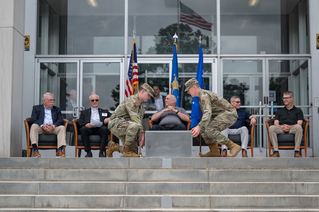 Senior Airman Christopher Bradbury, center left, and 1st Lt. Thomas Baldwin, center right, ceremonially seal the Arnold Engineering Development Complex time capsule unveiled June 27, 2026, during the AEDC 75th anniversary open house celebration at Arnold Air Force Base, Tenn., headquarters of AEDC. Former AEDC commander pictured seated, from left, are retired Air Force Col. Larry Graviss, retired Air Force Maj. Gen. Mike Wiedemer, retired Maj. Gen. Michael Brewer, retired Col. Raymond Toth and Maj. Gen. Scott Cain. (U.S. Air Force photo by Keith Thornburgh)