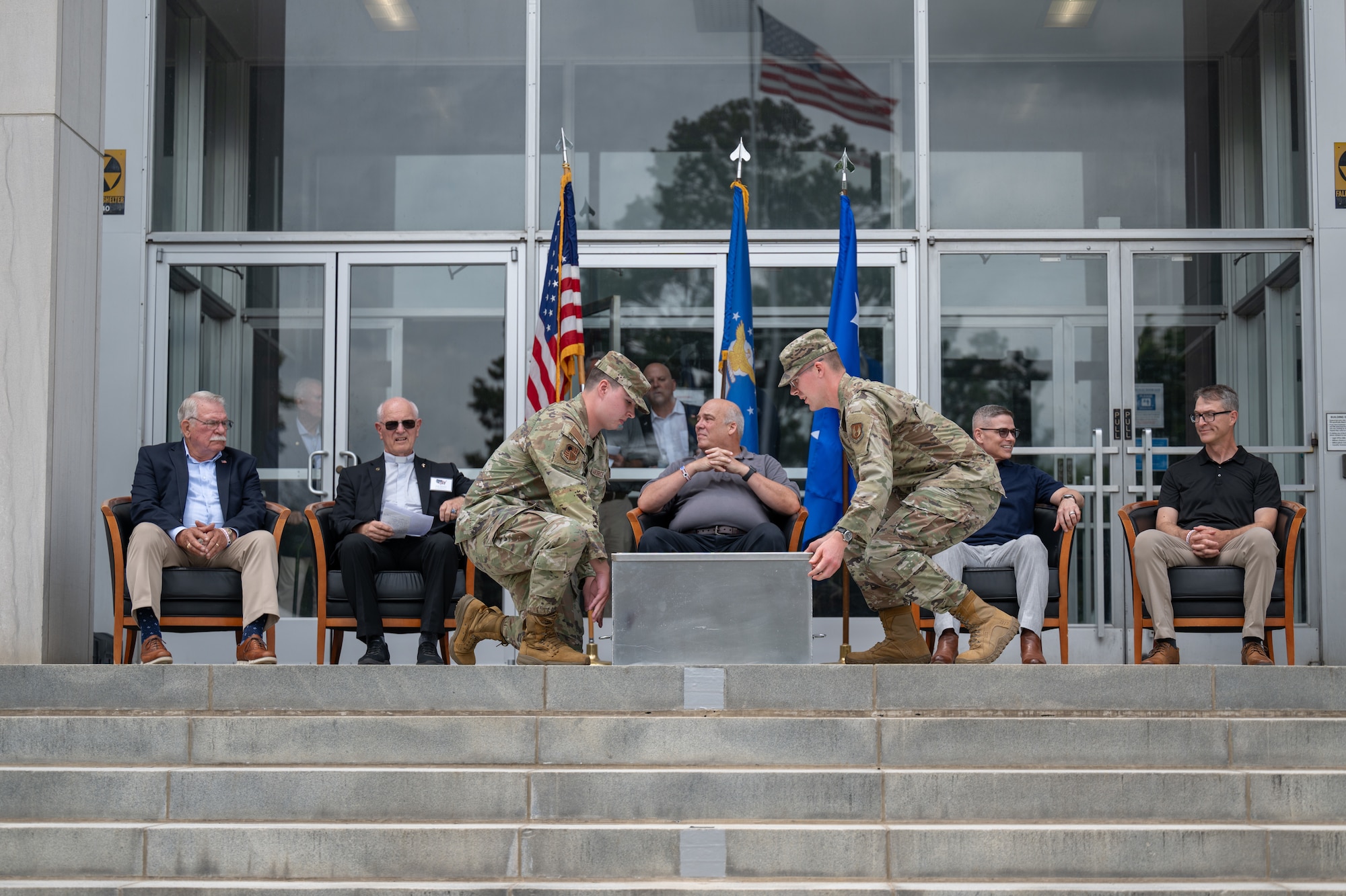 Senior Airman Christopher Bradbury, center left, and 1st Lt. Thomas Baldwin, center right, ceremonially seal the Arnold Engineering Development Complex time capsule unveiled June 27, 2026, during the AEDC 75th anniversary open house celebration at Arnold Air Force Base, Tenn., headquarters of AEDC. Former AEDC commander pictured seated, from left, are retired Air Force Col. Larry Graviss, retired Air Force Maj. Gen. Mike Wiedemer, retired Maj. Gen. Michael Brewer, retired Col. Raymond Toth and Maj. Gen. Scott Cain. (U.S. Air Force photo by Keith Thornburgh)