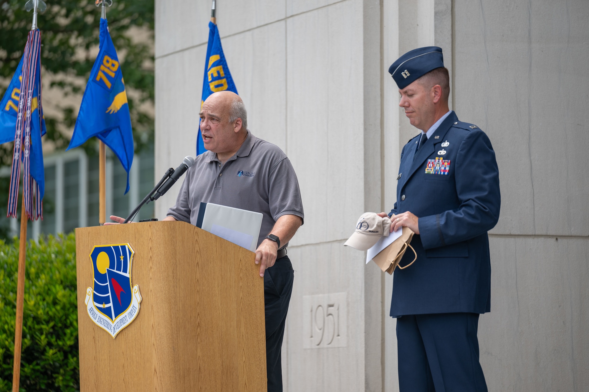 Retired Air Force Maj. Gen. and former Arnold Engineering Development Complex commander Michael Brewer, left, discusses the 60th anniversary hat and note he contributed to the AEDC time capsule unveiled June 27, 2026, during the AEDC 75th anniversary open house celebration at Arnold Air Force Base, Tenn., headquarters of AEDC. Brewer served as Complex commander when AEDC celebrated its 60th anniversary. Pictured holding the items contributed by Brewer is AEDC Executive Officer Capt. Nathan Tedder. (U.S. Air Force photo by Keith Thornburgh)
