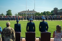 Three U.S. Air Force Colonels stand at attention facing The U.S. Air and Space Force Honor Guard.