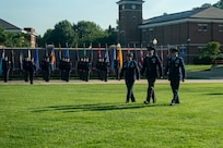 Two U.S. Air Force Colonels and a U.S. Space force Maj. walk across a field in front of The U.S. Space Force Honor Guard