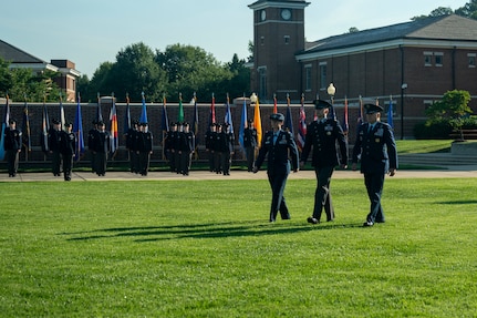 Two U.S. Air Force Colonels and a U.S. Space force Maj. walk across a field in front of The U.S. Space Force Honor Guard