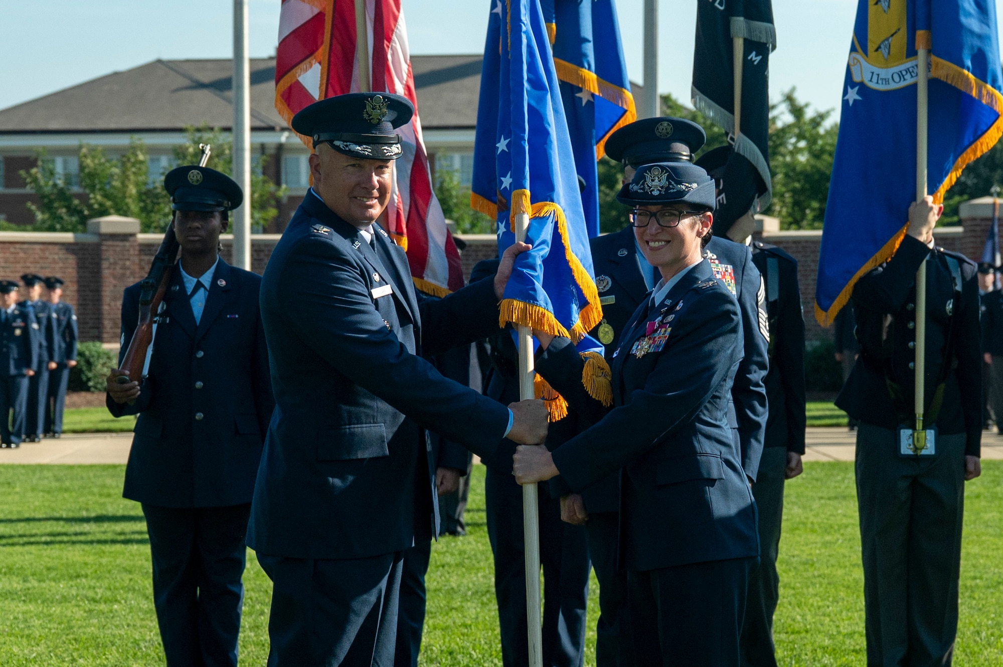 U.S. Air Force Col. passes guidon to another Col. in front of The U.S. Air and Space Force Honor Guard