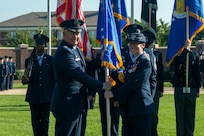 U.S. Air Force Col. passes guidon to another Col. in front of The U.S. Air and Space Force Honor Guard