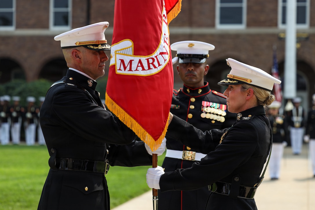 U.S. Marine Corps Col. Jason C. Copeland, incoming commanding officer of Marine Barracks Washington, left, receives the organizational colors from Col. Carrie C. Batson, outgoing commanding officer of MBW, during a change of command ceremony at Marine Barracks Washington, D.C., July 16, 2026. The ceremony included the passing of the organizational colors from the outgoing to the incoming commander, symbolizing the transfer of authority, responsibility, and accountability for the command, and featured marching and musical elements from Marine Barracks Washington. The ceremony took place as the “Oldest Post of the Corps” celebrates 225 years since its founding, a milestone that falls during America's 250th anniversary of independence and just one year after the Marine Corps 250th birthday. (U.S. Marine Corps photo by Lance Cpl. Landon Heredia)