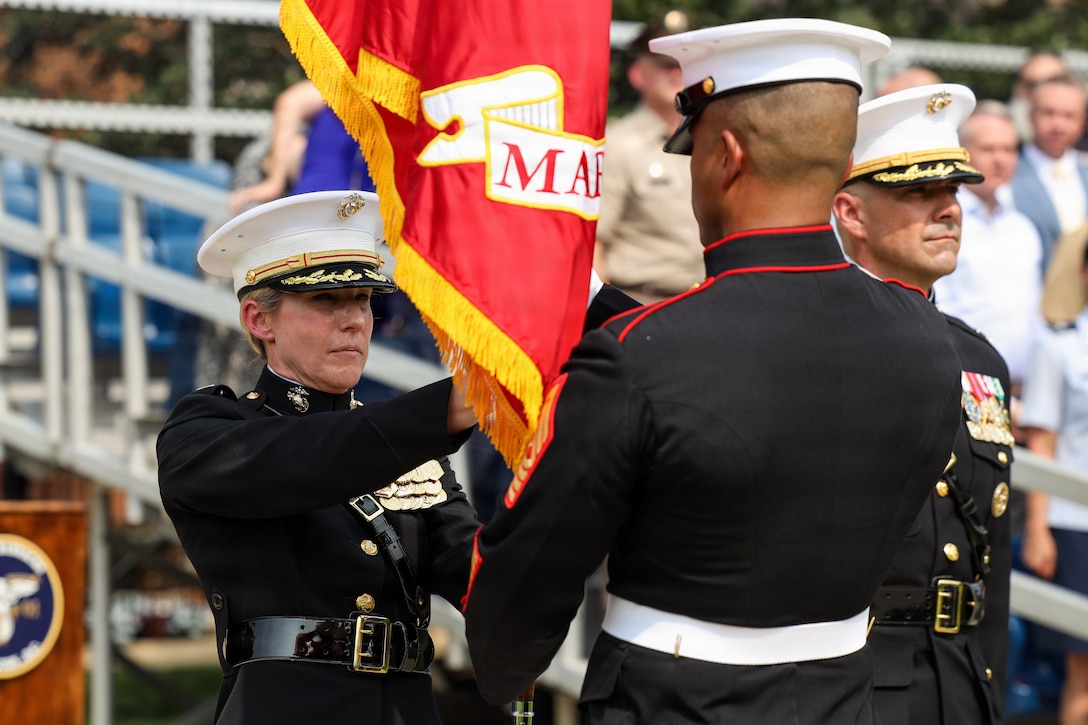U.S. Marine Corps Col. Carrie C. Batson, outgoing commanding officer of Marine Barracks Washington, left, receives the organizational colors from Sgt. Maj. Juan P. Segura, sergeant major of MBW, during a change of command ceremony at Marine Barracks Washington, D.C., July 16, 2026. The ceremony included the passing of the organizational colors from the outgoing to the incoming commander, symbolizing the transfer of authority, responsibility, and accountability for the command, and featured marching and musical elements from Marine Barracks Washington. The ceremony took place as the “Oldest Post of the Corps” celebrates 225 years since its founding, a milestone that falls during America's 250th anniversary of independence and just one year after the Marine Corps 250th birthday. (U.S. Marine Corps photo by Lance Cpl. Landon Heredia)
